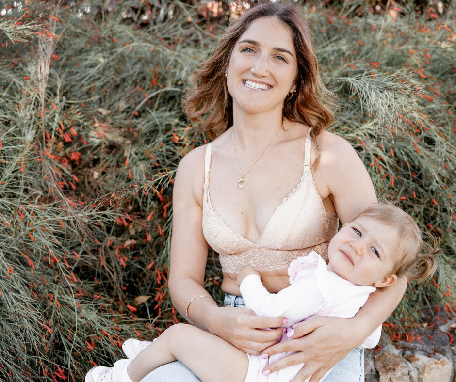 Woman wearing lace nursing bra, holding a baby.