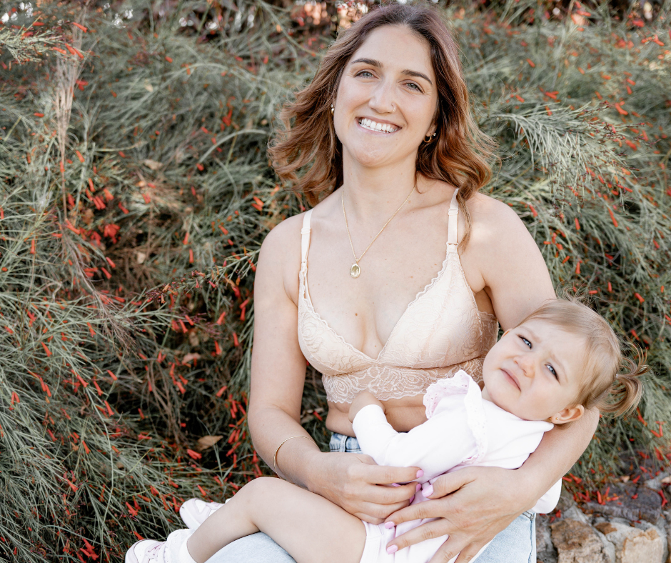 Woman wearing lace nursing bra, holding a baby. 